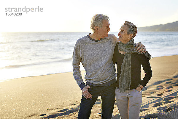 Glückliches älteres Ehepaar am Strand bei Sonnenuntergang