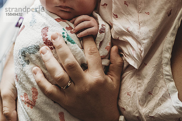 Makro-Draufsicht einer Mutter  die im Krankenhaus die Finger eines neugeborenen Jungen hält