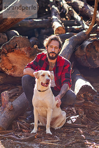 Porträt eines jungen tätowierten Mannes mit seinem Hund im Wald