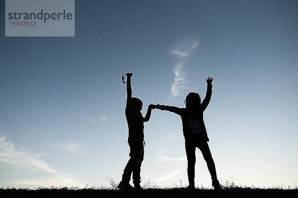 Silhouettierte Kinder spielen auf einem Hügel in Waco  Texas