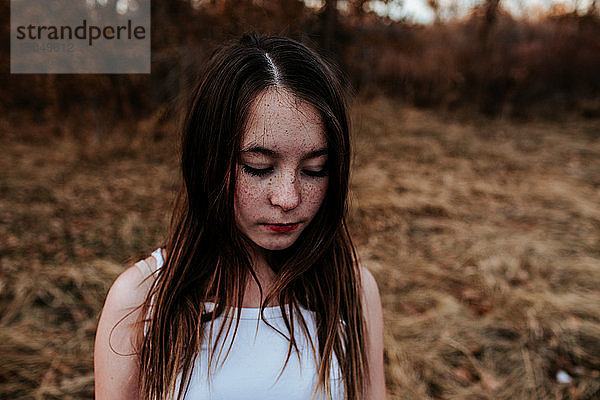 Porträt eines sommersprossigen jungen Mädchens  das auf ein Feld blickt