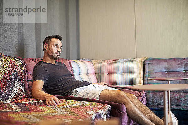 Ein Mann entspannt sich auf einer bequemen modernen Couch.