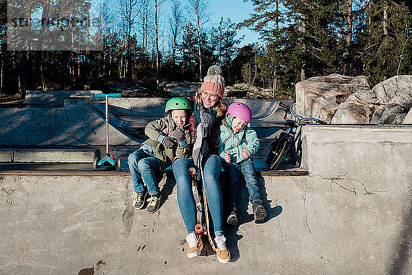 Mama spielt mit ihren Kindern in einem Skatepark im Freien und hat Spaß