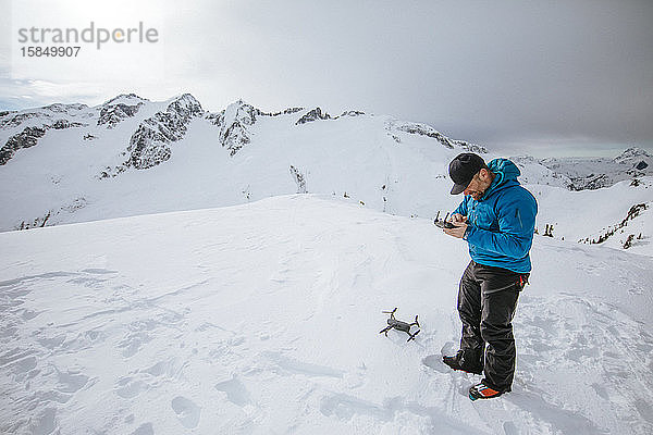 Mann bereitet den Einsatz einer Drohne auf schneebedecktem Berg vor.