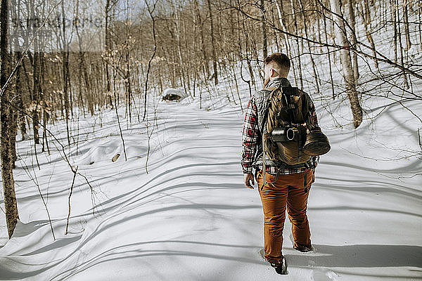 Mann mit Segeltuch-Rucksack wandert durch tiefen Schnee in den Wäldern von Maine