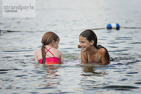 Zwei junge Mädchen im Badeanzug spielen in einem See