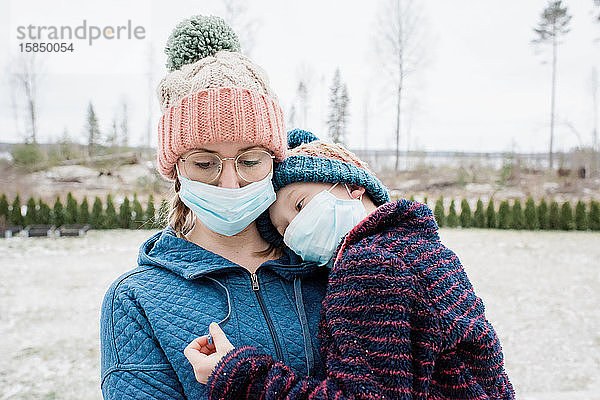 Mutter  die ihren Sohn mit Gesichtsmasken zum Schutz vor Virus und Grippe trägt