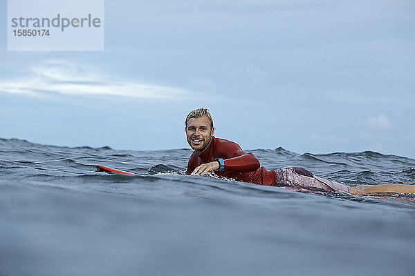 Auf einem Surfbrett auf dem Meer liegender Mann