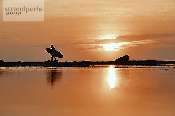 Silhouette eines Surfers bei Sonnenuntergang am Strand