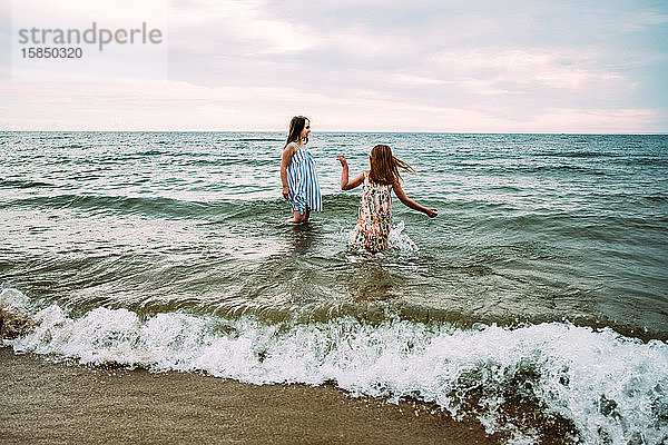 Mädchen spielen am Sommertag voll bekleidet im Lake Michigan