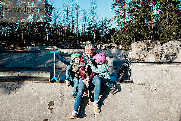 Mama und ihre Kinder lachen und haben Spaß in einem Skatepark