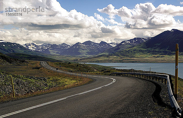 Einsame Straße in einem Fjord mit hohen Bergen im Hintergrund in Island
