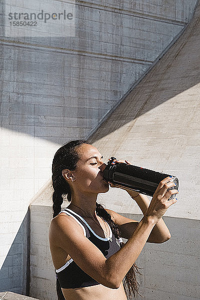 Weibliche Sportlerin trinkt im Ruhezustand Wasser