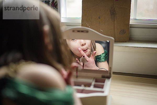 Ein kleines Mädchen betrachtet ihr Spiegelbild in einem Spiegel einer Schmuckschatulle