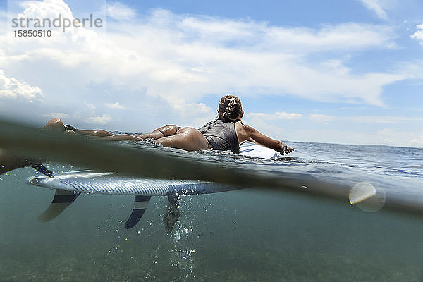 Frau liegt auf einem Surfbrett auf dem Meer