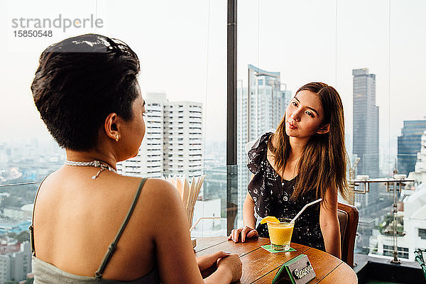 Frauen sitzen an einer Rooftop Bar