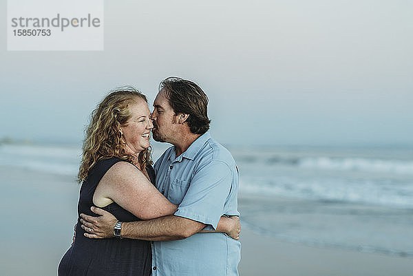 Seitenansicht von Mann und Frau  die sich am Strand küssen