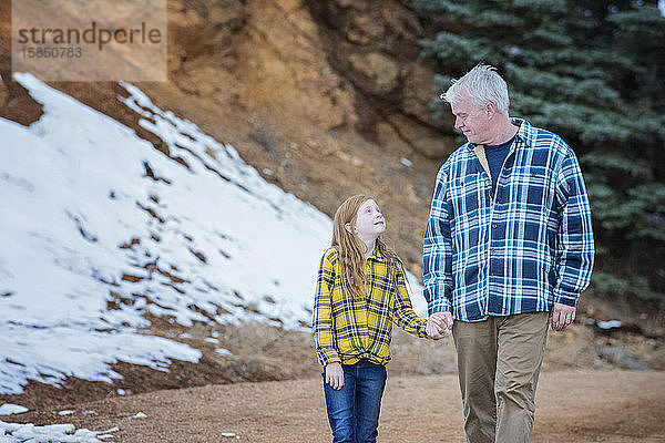 Grossvater und Enkelin beim Händewandern in den Bergen
