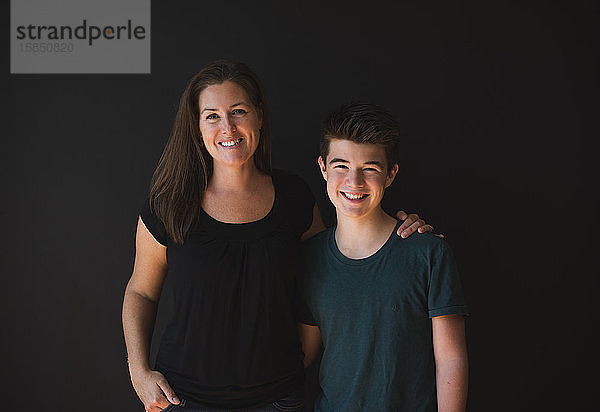 Porträt eines Teenagers und seiner Mutter vor einem dunklen Hintergrund.