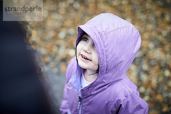 Ein fröhliches Porträt eines kleinen Mädchens im Freien im Regen.