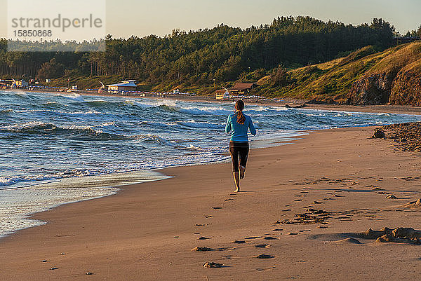 Junges sportliches Mädchen läuft am Strand