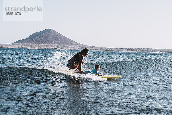 Zurückgezogene Ansicht von Mutter und Sohn beim Surfen auf einer kleinen Welle auf See