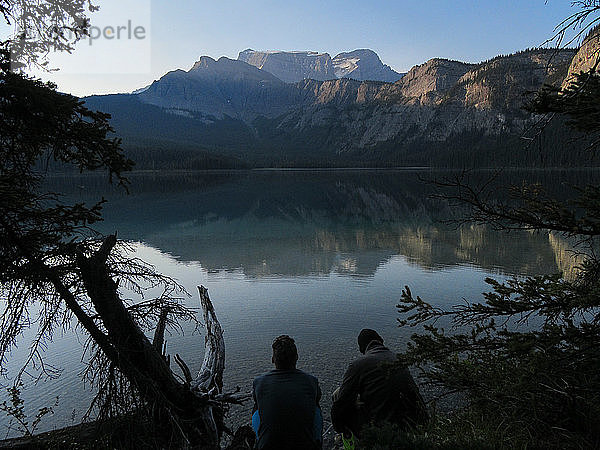 Zwei Freunde am frühen Morgen am stillen See in den Rocky Mountains