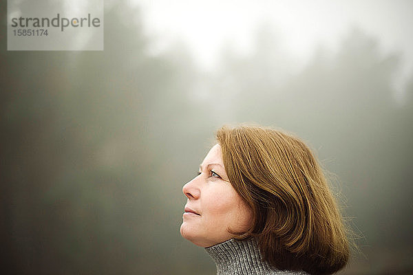 Frau steht bei nebligem Wetter am Wald