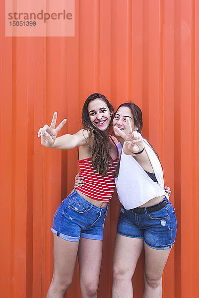 Zwei glückliche  fröhliche Teenager-Mädchen zeigen Friedensgeste