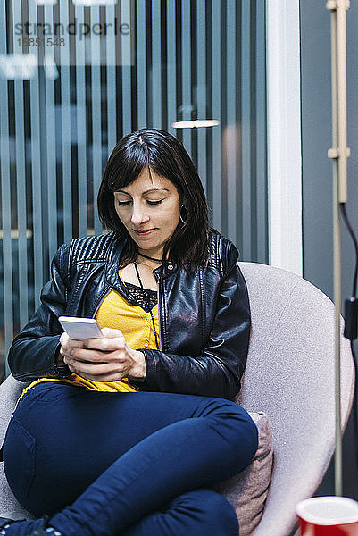 Textnachrichten einer Geschäftsfrau auf einem Mobiltelefon in einem Büro