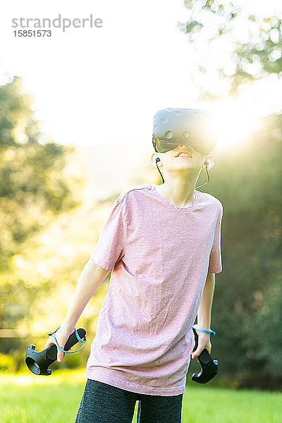 Zwischenmensch mit virtueller Erfahrung mit VR-Brille draußen auf der grünen Wiese