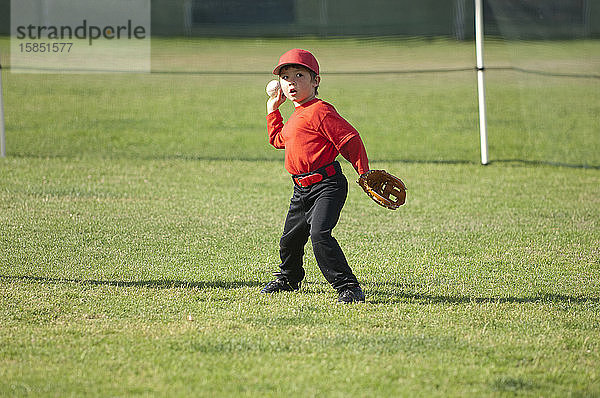 Junge wirft einen Baseball auf dem TBall-Feld