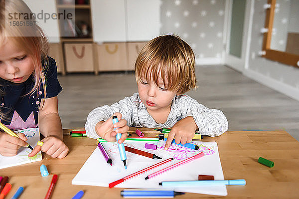 Kleiner Junge mit Schwester zeichnet mit Filzstiften