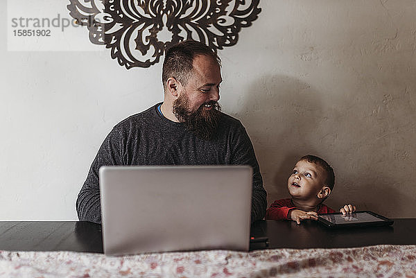 Arbeit zu Hause Vater arbeitet mit jungem Kleinkind während der Isolation