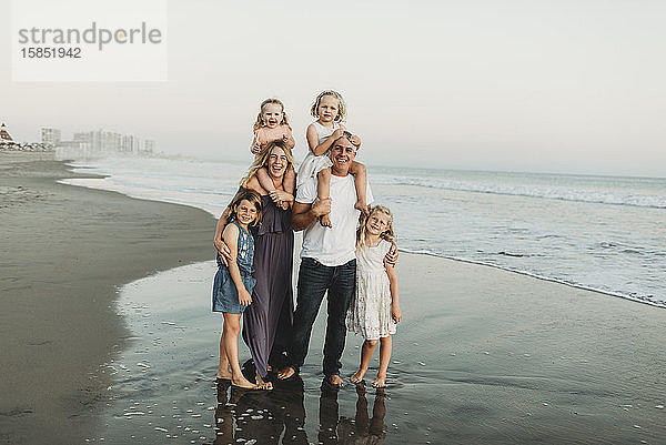 Traditionelles Porträt einer Familie mit vier Kindern  die in der Strandsonne lächeln