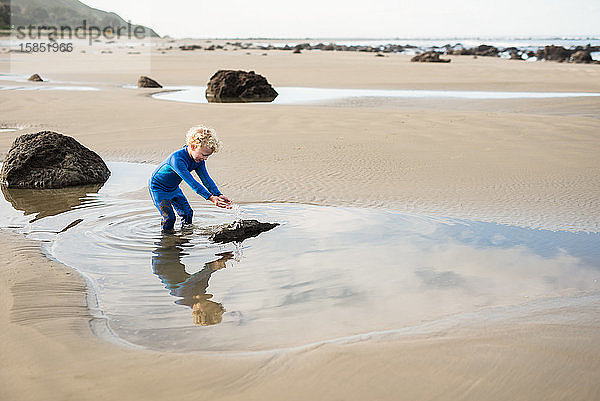 Junge spritzt Wasser am neuseeländischen Strand