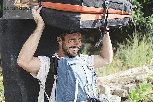 Porträt eines Bergsteigers mit Crashpad und Rucksäcken