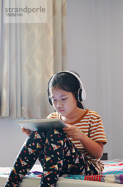 Mädchen benutzen ein Tablett und hören Musik mit Kopfhörern