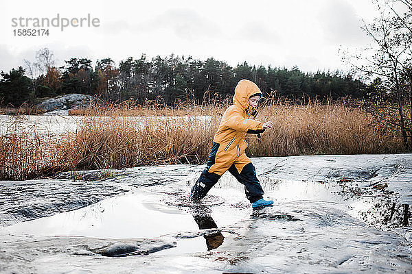 Junge springt und spielt im Wasser auf einer Insel in Schweden