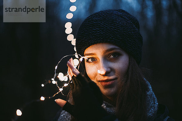 Nahaufnahme eines Porträts einer schönen jungen Frau mit Weihnachtsbeleuchtung