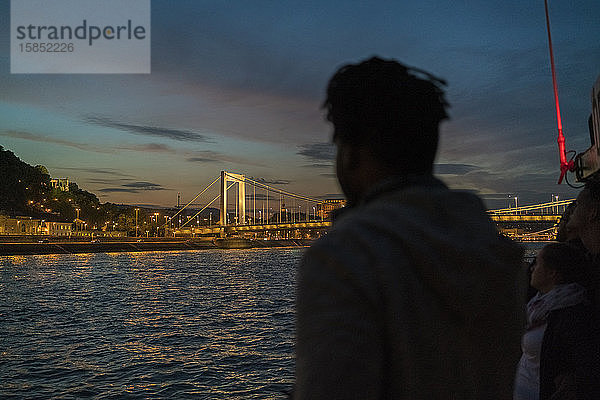 Afrikanischer Mann fotografiert nachts die beleuchtete Elisabeth-Brücke