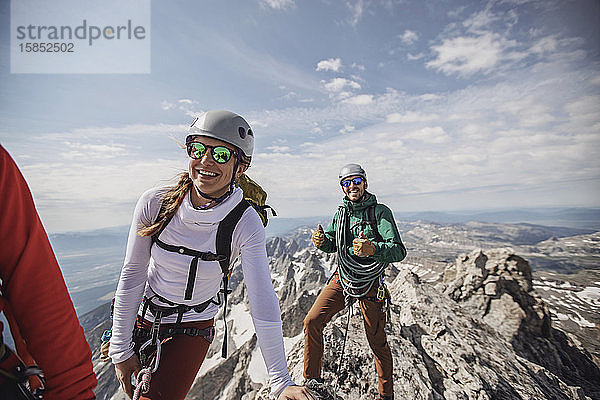 Drei Bergsteiger lächeln nach Erreichen des Gipfels des Grand Teton