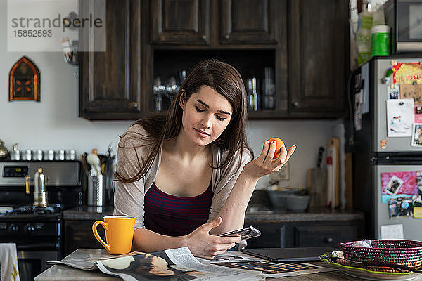 Frau liest Zeitung beim Frühstück am Tisch in der Küche