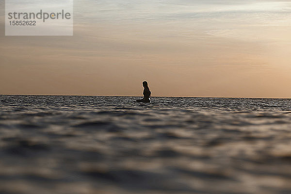 Weibliche Surferin bei Sonnenuntergang im Ozean