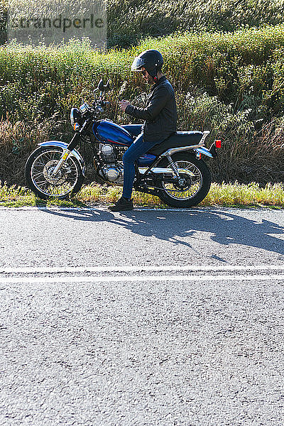 junger Mann  der sich die Route ansieht  der er auf seinem Motorrad mit dem Mo