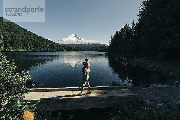 Ein Vater trägt seine Tochter am Trillium Lake  OR  auf den Schultern.