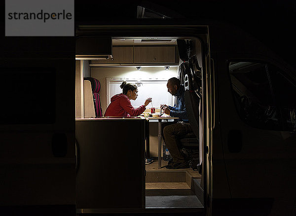 Ehepaar bei einem entspannten Abendessen in einem Wohnmobil während einer Reise.