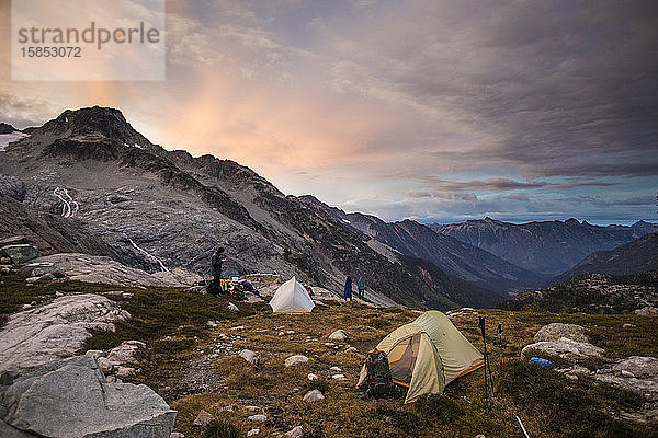 Bergsteiger zelten auf einer Almwiese unterhalb des Berges.