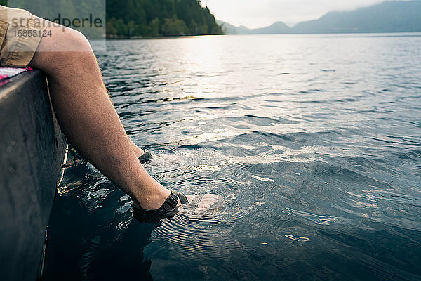Männerfüsse in Sandalen in den See getaucht