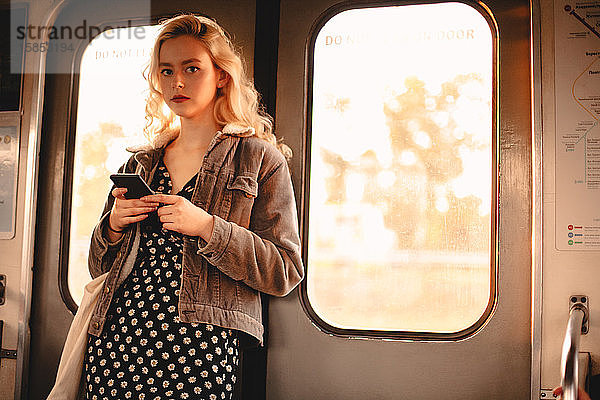 Junge Frau benutzt Smartphone während der Fahrt in der U-Bahn